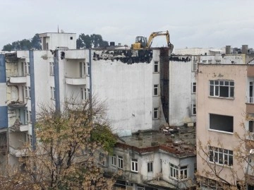 İş makinası yıkım için ağır hasarlı binanın üzerine çıkarıldı